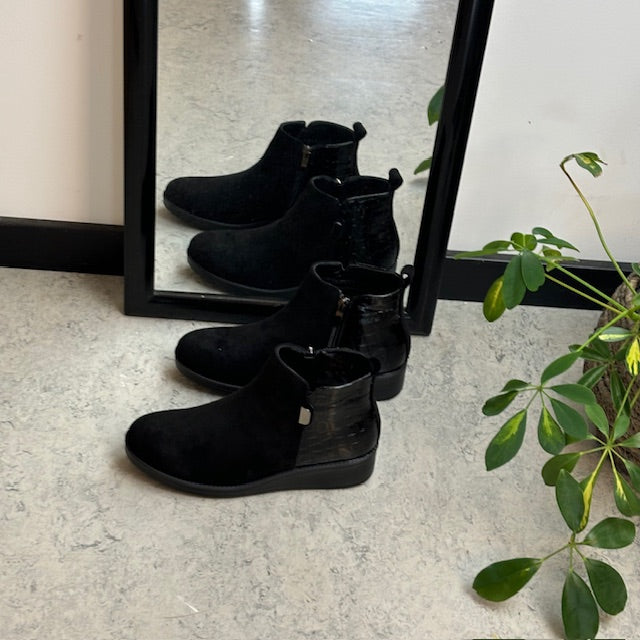Kort svart stövel med lackdetaljer vid hälen