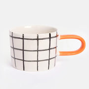 Modern mugg med rutigt mönster och orange handtag – stilren design för kaffe & te