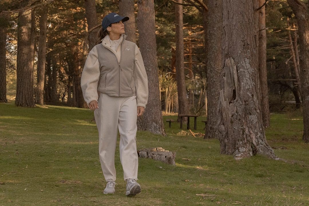 Kvinde går i skoven iført MBT Colorado X White Grey sneakers og outdoor-tøj. Ergonomisk fodtøj med rullesål.