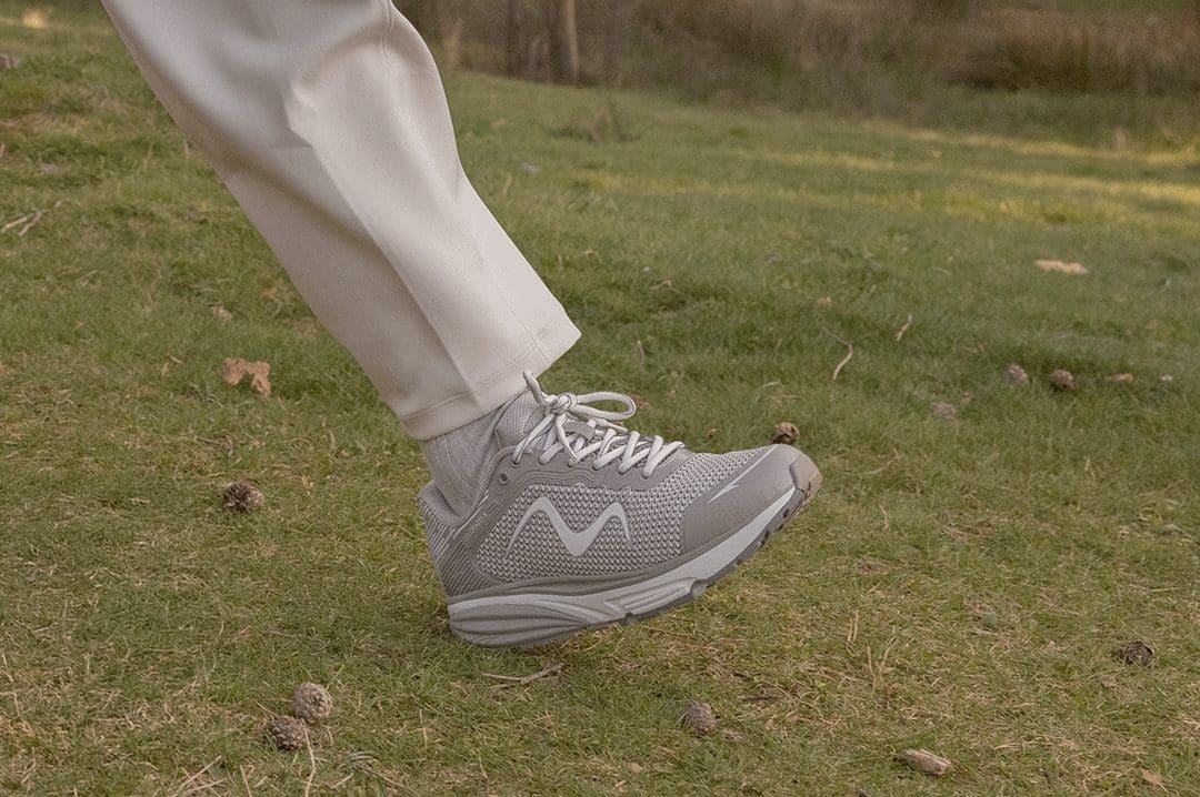 MBT Colorado X White Grey dame sneaker på græs. Fysiologisk sko med rullesål til aktiv hverdag.